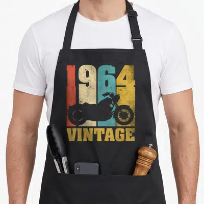 Tablier de cuisine noir avec chiffres 1964 multicolores et silhouette de moto vintage au centre.
