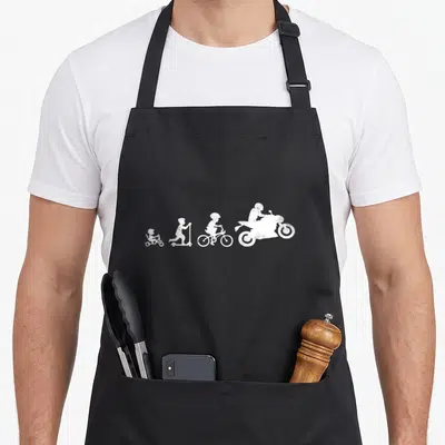 Tablier de cuisine noir avec une illustration blanche montrant la progression d'un enfant vers un pilote de moto.