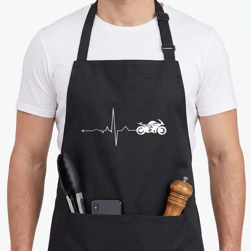 Tablier de cuisine noir avec une ligne de vie blanche se terminant par le dessin d'une moto sport.