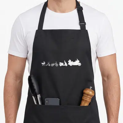 Tablier de cuisine noir avec une série blanche représentant l'évolution d'une poussette à une grande moto de tourisme.