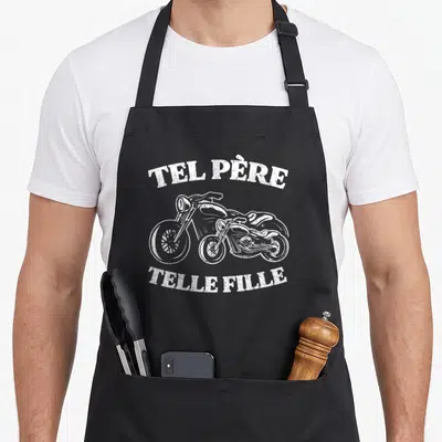 Tablier de cuisine noir avec illustration de motocyclette et texte Tel Père Telle Fille en blanc.