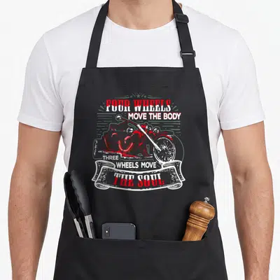 Tablier de cuisine noir avec illustration trike et texte Three Wheels Move the Soul en rouge et blanc.
