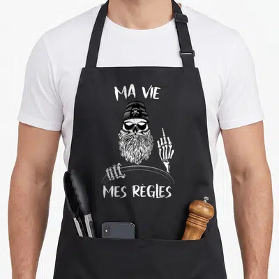 Tablier de cuisine noir avec illustration squelette barbu portant un bonnet et des lunettes de soleil.