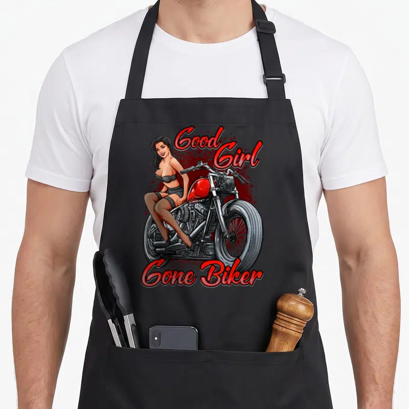 Tablier de cuisine noir avec illustration pin up femme sur moto custom rouge et texte Good Girl Gone Biker en lettres rouges.