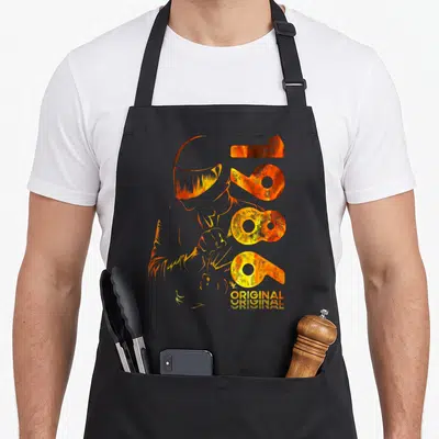 Tablier de cuisine noir avec illustration orange d'un motard casqué et les chiffres 1986 Original imprimés en typographie stylisée.