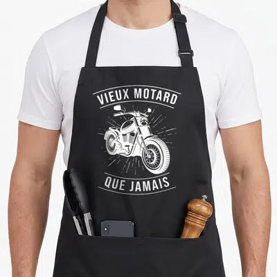 Tablier de cuisine noir avec un motif blanc représentant une moto chopper et le texte VIEUX MOTARD QUE JAMAIS.