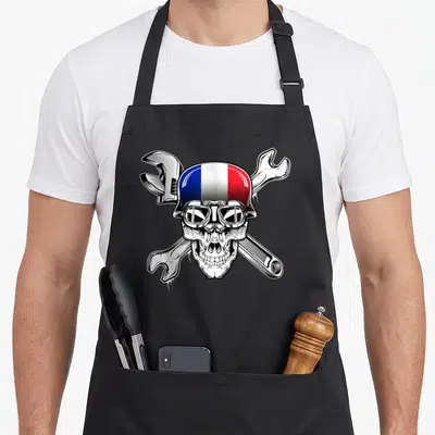 Tablier de cuisine noir avec crâne casque tricolore et clés anglaises croisées en illustration détaillée.