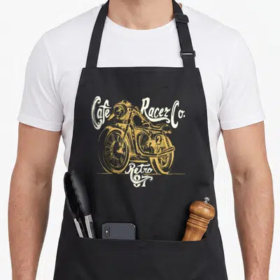 Tablier de cuisine noir avec illustration jaune d'une moto vintage et le texte Cafe Racer Co Retro 97 en blanc.