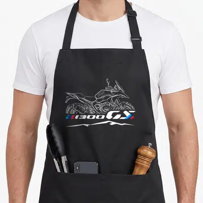 Tablier de cuisine noir avec une illustration blanche d’une moto R1300 GS surmontant un motif de montagnes stylisées.