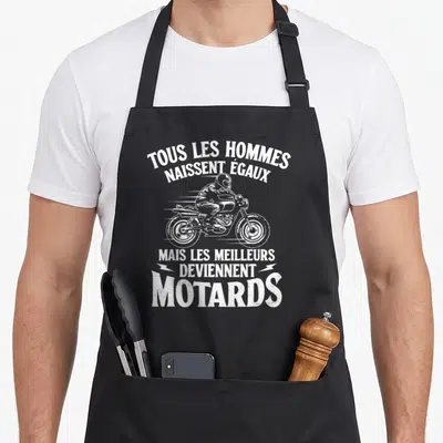 Tablier de cuisine noir avec illustration blanche d'un motard et texte humoristique sur la passion cycliste.