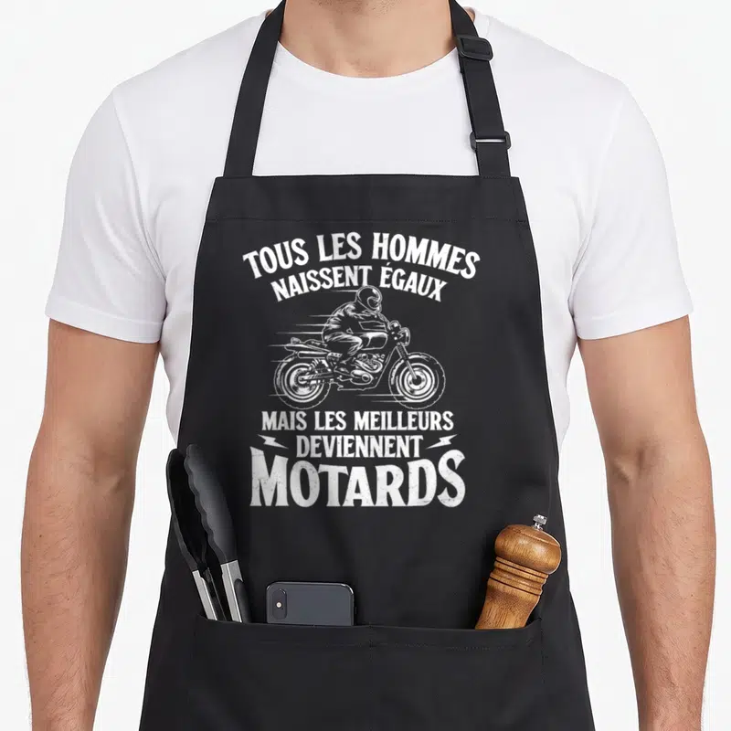 Tablier de cuisine noir avec illustration blanche d'un motard et texte humoristique sur la passion cycliste.