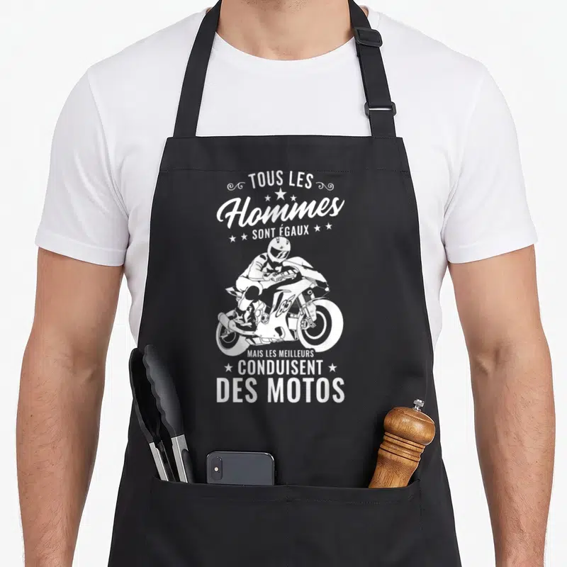 Tablier de cuisine noir avec illustration blanche d'un pilote de moto et le texte Tous les Hommes sont Égaux mais Conduisent des Motos.