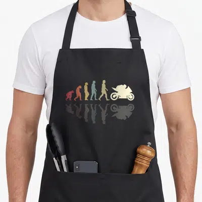Tablier de cuisine noir avec une illustration colorée représentant l'évolution de l'homme jusqu'à un motard en silhouette blanche.