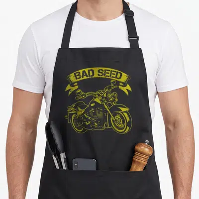 Tablier de cuisine noir avec illustration jaune d'une moto custom et banderole Bad Seed en style rétro.
