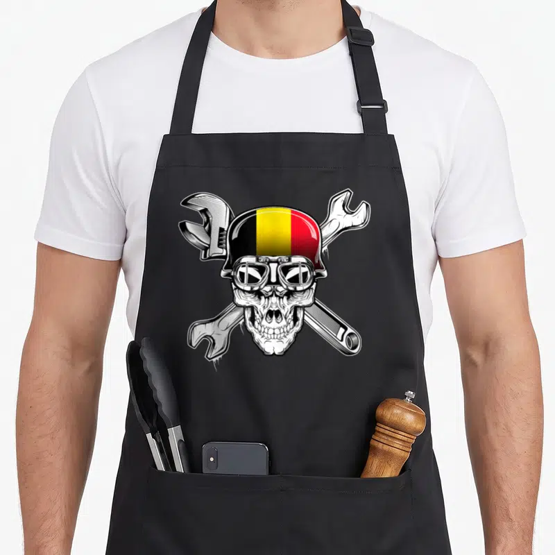 Tablier de cuisine noir avec un crâne casqué belge et des clés anglaises croisées en illustration.