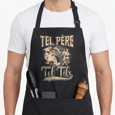 Tablier de cuisine noir avec illustration vintage d'un père et d'un fils en tenue de motocross sur fond strié beige.