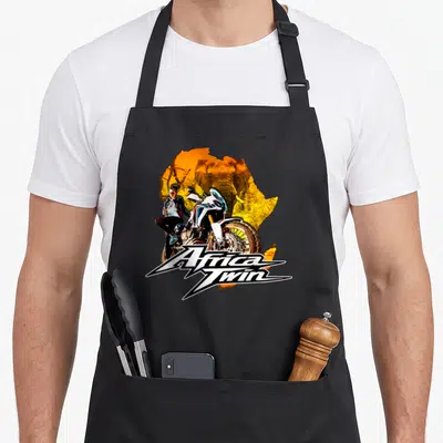Tablier de cuisine noir avec illustration d'une femme moto et logo Africa Twin sur fond Afrique orange.
