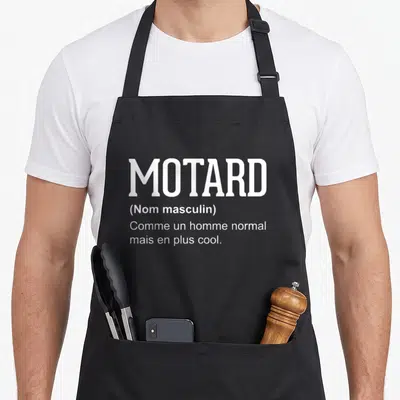 Tablier de cuisine noir avec le mot Motard défini comme un homme normal mais en plus cool en typographie blanche.