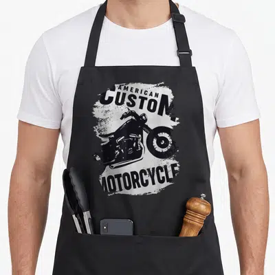 Tablier de cuisine noir avec illustration blanche d'une moto custom et texte American Custom Motorcycle.