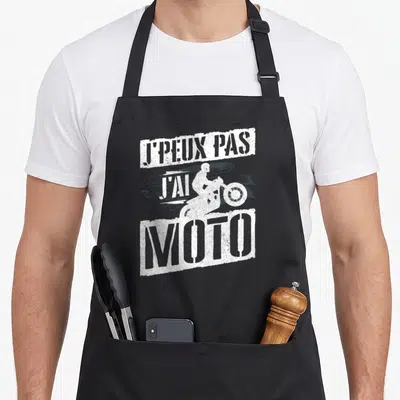 Tablier de cuisine noir avec inscription J'peux pas j'ai moto et silhouette de motard sur traces de pneu.