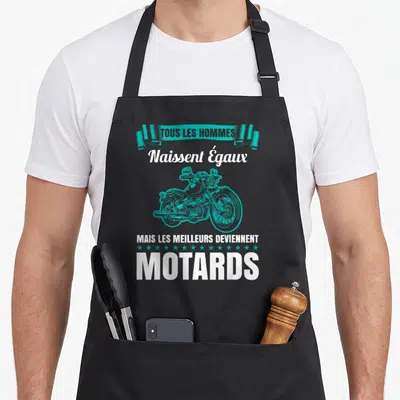 Tablier de cuisine noir avec une moto turquoise et le texte Tous les hommes naissent égaux mais les meilleurs deviennent motards.