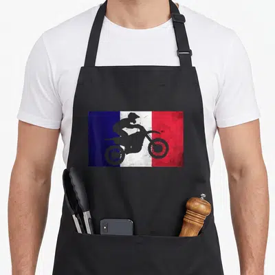 Tablier de cuisine noir avec illustration d'un pilote de moto sur un drapeau français aux couleurs bleue, blanche et rouge.