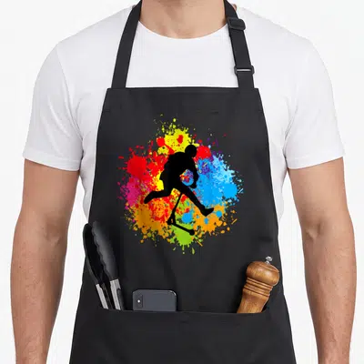 Tablier de cuisine noir avec silhouette noire d'enfant sur scooter devant un fond multicolore d'éclaboussures.