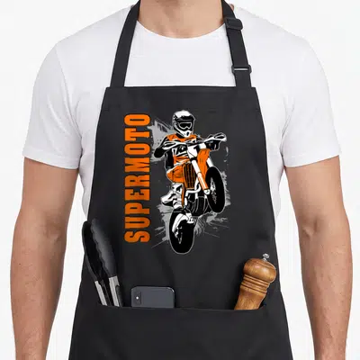 Tablier de cuisine noir avec illustration orange d'un supermotard en wheelie et texte SUPERMOTO vertical.
