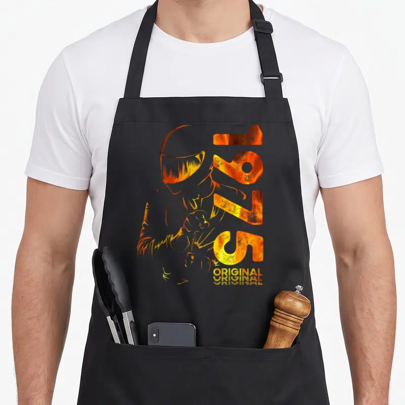 Tablier de cuisine noir avec illustration d'un motord casqué et les chiffres 1975 en orange brûlé ainsi que le mot original.