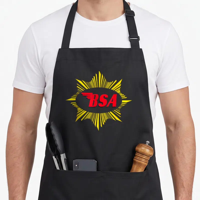 Tablier de cuisine noir avec le logo BSA rouge et des rayons jaunes émanant du texte central.