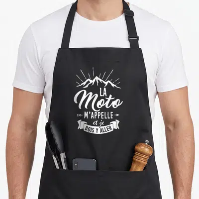 Tablier de cuisine noir avec inscription blanche la Moto m'appelle et je dois y aller au-dessus d'un motif de montagnes.