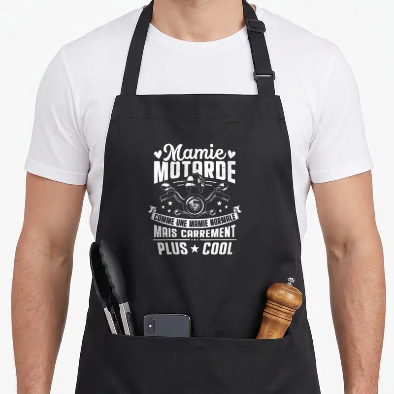 Tablier de cuisine noir avec illustration blanche Mamie Motarde guidon et casque vintage.