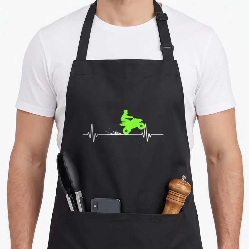 Tablier de cuisine noir avec silhouette verte d'un quad sur une ligne de rythme cardiaque blanche.