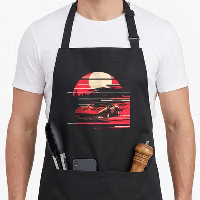 Tablier de cuisine noir avec illustration d'une voiture de sport rouge stylisée devant un soleil couchant à rayures horizontales.