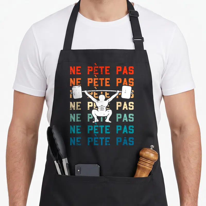 Tablier de cuisine noir avec une silhouette blanche effectuant un squat sous barre et des textes colorés superposés.