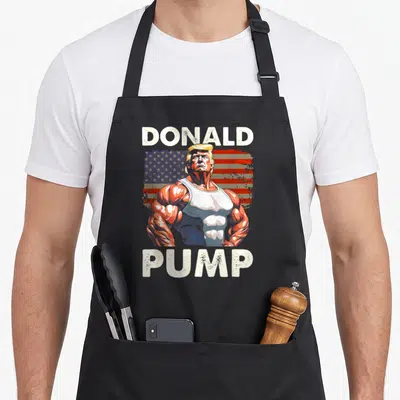 Tablier de cuisine noir avec illustration musclée Donald Pump et drapeau américain en arrière-plan.