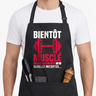 Tablier de cuisine noir avec illustration de barre rouge et texte Bientôt Musclé Veuillez Patienter en blanc.