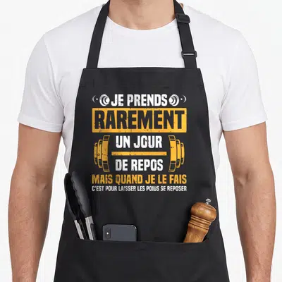 Tablier de cuisine noir avec texte blanc et orange sur la musculation et un barre d'haltere stylisée au centre.