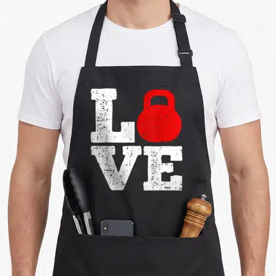 Tablier de cuisine noir avec le mot Love en blanc et une haltère rouge remplaçant la lettre O