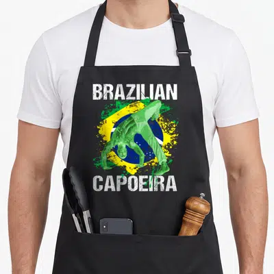 Tablier de cuisine noir avec un homme vert en capoeira devant un drapeau brésilien et le texte Brazilian Capoeira.