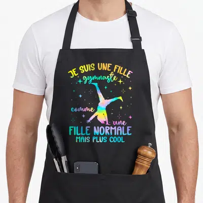 Tablier de cuisine noir avec une gymnaste aquarelle et le texte Je suis une fille gymnaste comme une fille normale mais plus cool.