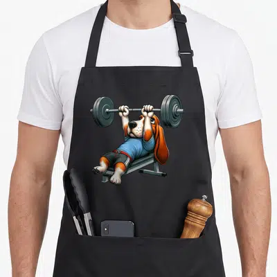 Tablier de cuisine noir avec illustration d'un basset hound effectuant un bench press avec une barre de poids.