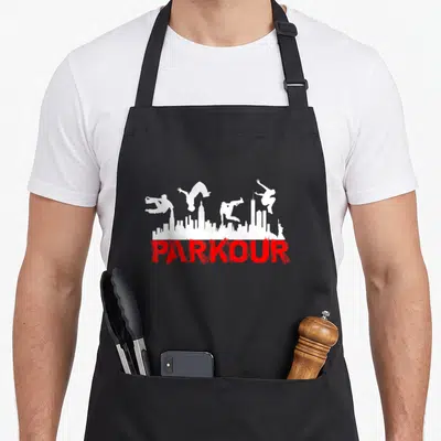 Tablier de cuisine noir avec silhouettes de parkouristes et skyline blanc au-dessus du mot PARKOUR en rouge.