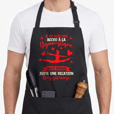 Tablier de cuisine noir avec silhouette rouge de gymnaste et texte humoristique sur la gymnastique rythmique.