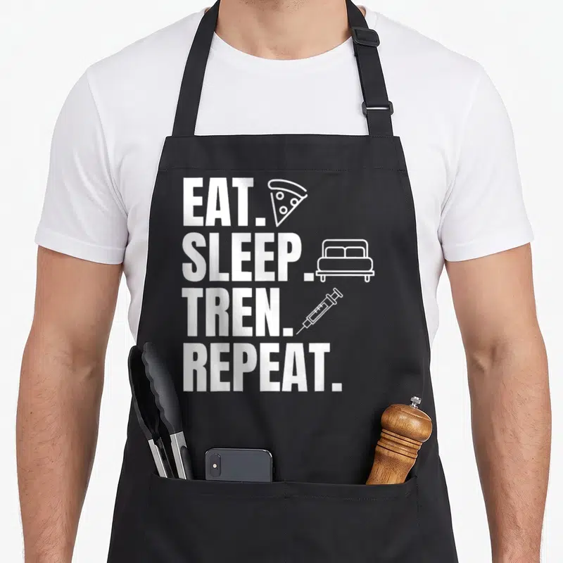 Tablier de cuisine noir avec texte blanc Mangez Dormez Tren Repeat et icônes pizza lit seringue.