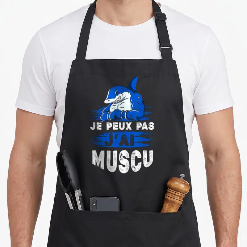 Tablier de cuisine noir avec un requin bleu musclé et le texte Je Peux Pas J'ai Muscu imprimé en blanc.