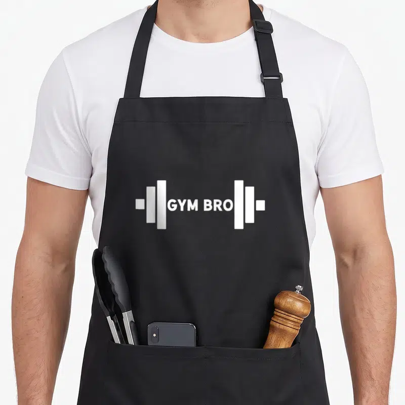 Tablier de cuisine noir avec une barre de fer blanche et l'inscription Gym Bro au centre.