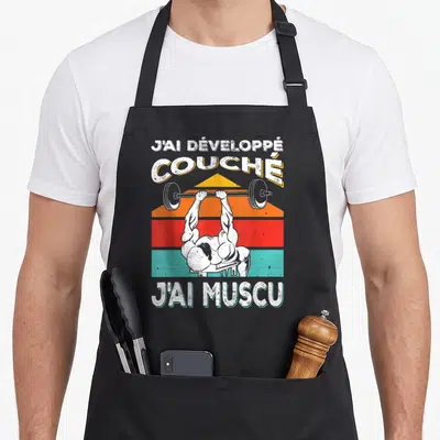 Tablier de cuisine noir avec illustration d'un culturiste effectuant un développé couché sur fond de bandes colorées vintage.