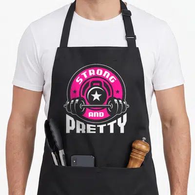Tablier de cuisine noir avec logo Strong And Pretty, barre d'haltère et kettlebell rose vif.
