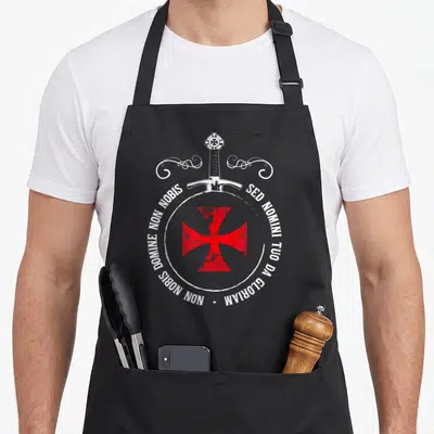 Tablier de cuisine noir avec une croix rouge templier, une épée blanche et une inscription latine circulaire.